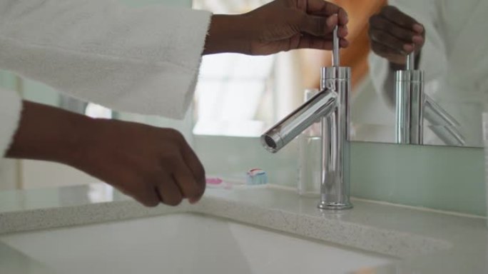 非裔美国迷人女人的手在浴室的刷子上涂抹牙膏