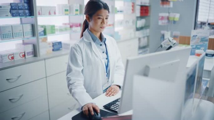 药房药店: 美丽的亚洲药剂师使用收银台电脑，做库存检查，在线处方的药品包装，药品，维生素盒，补充剂，