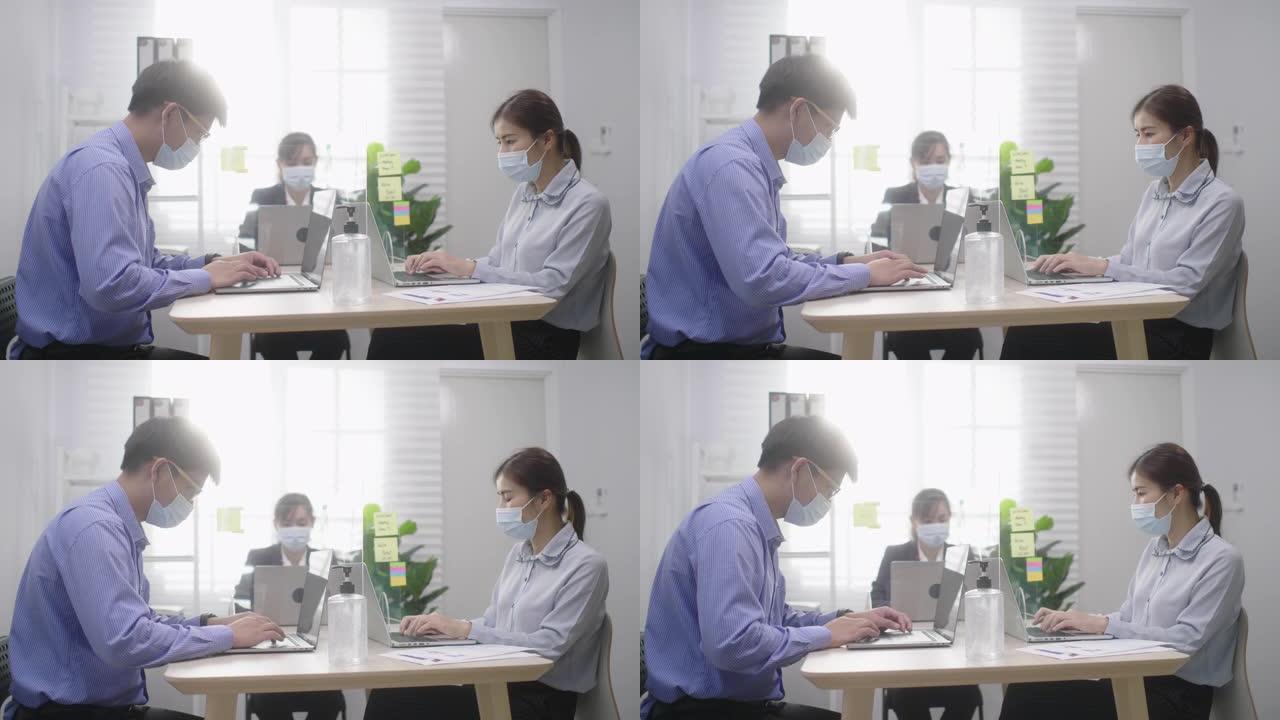 亚洲商人企业家戴着口罩，在新的正常情况下保持社交距离，以防止病毒在办公室工作时使用笔记本电脑洗手。电