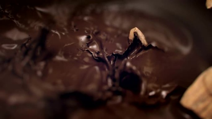 杏仁坚果在4k超慢动作中落入液态黑巧克力中
