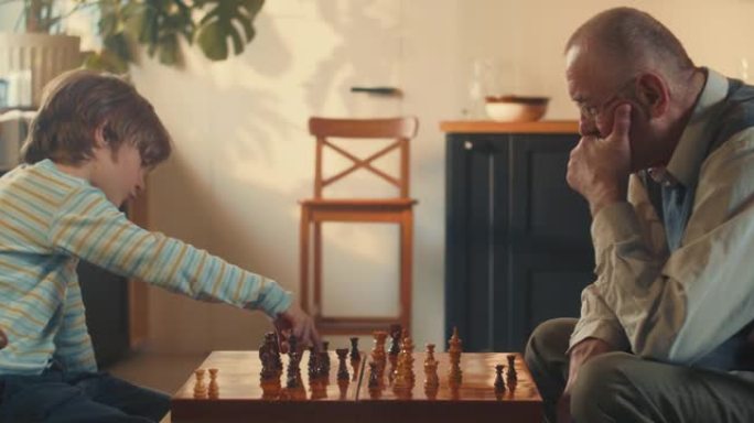 小天才。侧视图男孩孩子在光之家与老祖父下棋。发展智力概念。