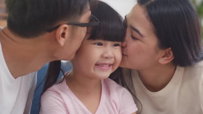 快乐的亚洲家庭爸爸、妈妈和女儿拥抱亲吻脸颊祝贺家里的生日。