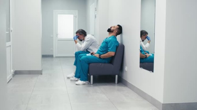 压力大的男医生坐在诊所走廊的沙发上