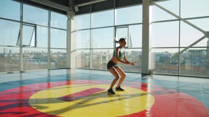 适合年轻的女士在带全景窗户的现代阳光健身房里跳起来锻炼