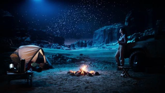 女性旅行者在篝火旁露营时看着夜空。令人惊叹的银河明星露营地景观，旅行中的女性冒险家在鼓舞人心的自然之