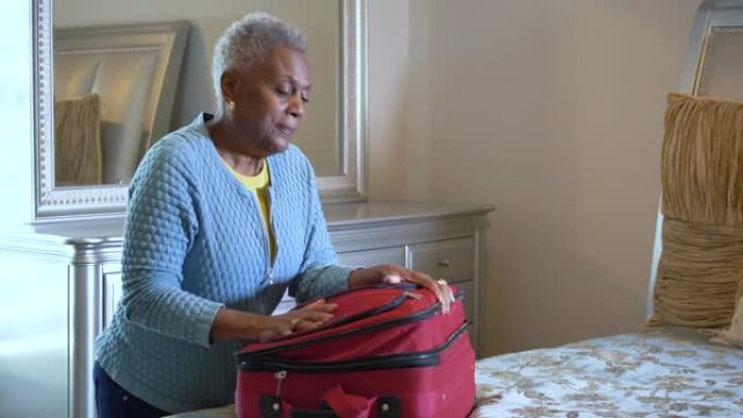 高级非裔美国妇女在卧室里打包行李箱