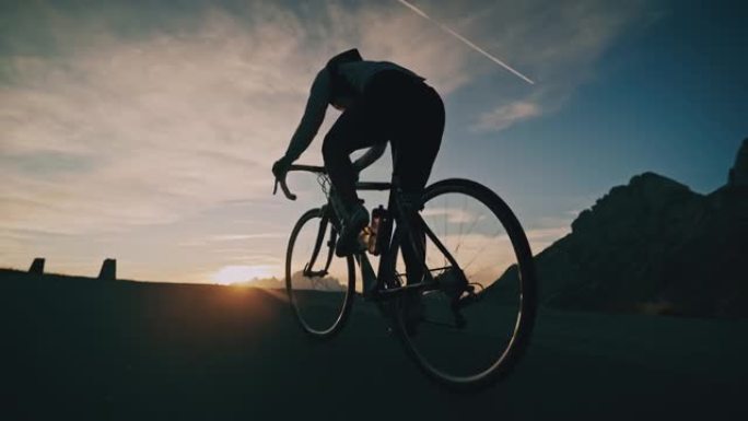 骑自行车的人在日出山上的道路上骑自行车