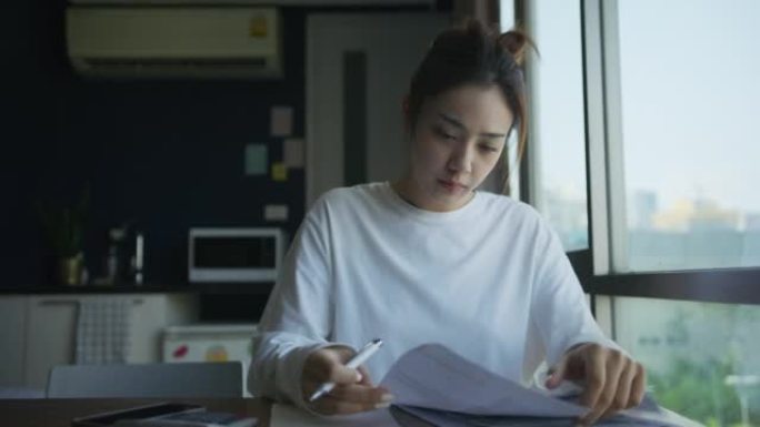 亚洲妇女检查帐单和使用计算器计算