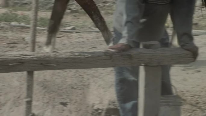 马驱动的磨坊，在阿根廷圣地亚哥德尔埃斯特罗省一个贫穷的牧场里，一匹马的腿拉着木头。低角度视图。