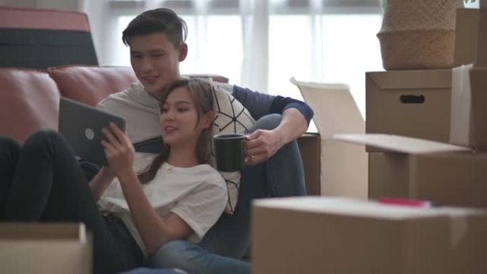 亚洲中国夫妇在客厅搬家房中打开纸箱纸箱后坐在地板上休息