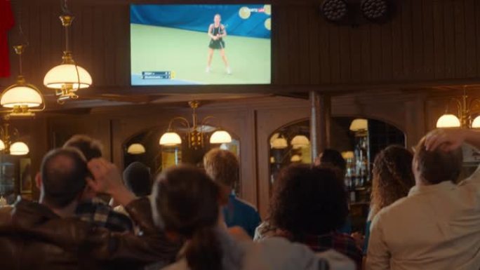 一群网球迷在电视上的体育酒吧观看国际直播。人们欢呼，支持他们的球员。当运动员进球并赢得冠军时，人群会