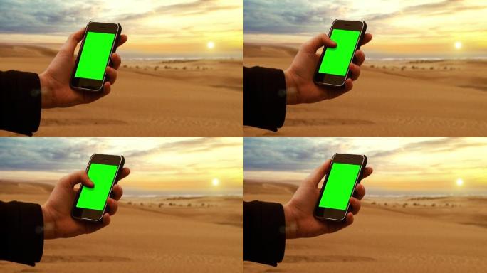日落时，手持旧手机绿屏在海滩上。特写。