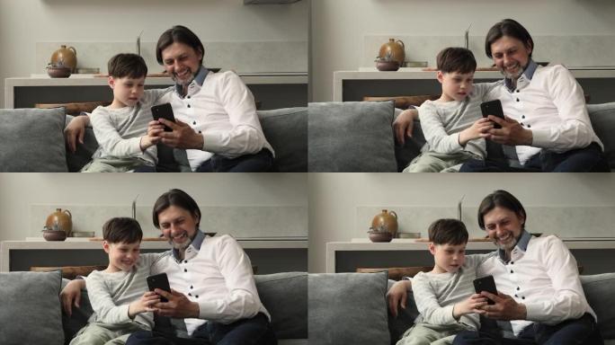 爸爸和8s儿子一起使用智能手机坐在沙发上