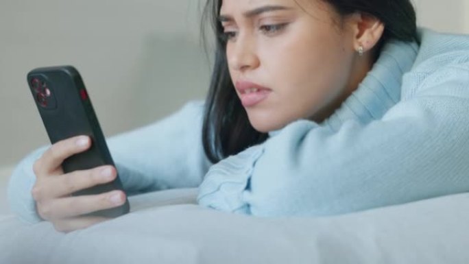 电话、压力和坏消息，女人躺在卧室的床上发短信，看起来很沮丧。女性通过检查智能手机而烦恼，故障和网络问