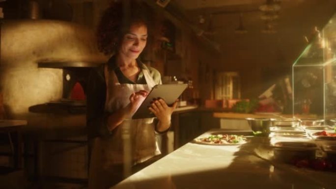 餐厅: 美丽的女厨师使用数字平板电脑。正宗的比萨店，配有美味的有机生态食品。在她的小型企业家庭商店工