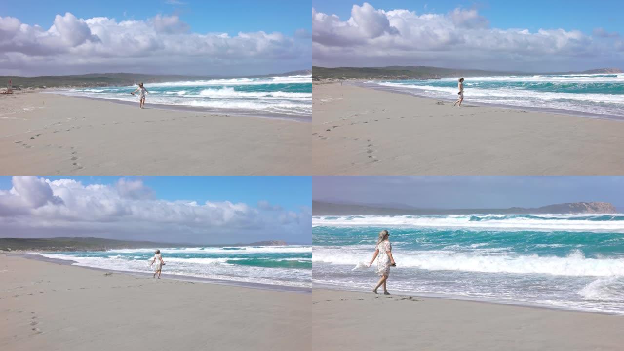 撒丁岛海滩上散步的金发女孩的慢动作视图。
