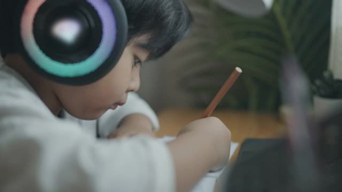 一个戴着耳机的男孩在家上网学习