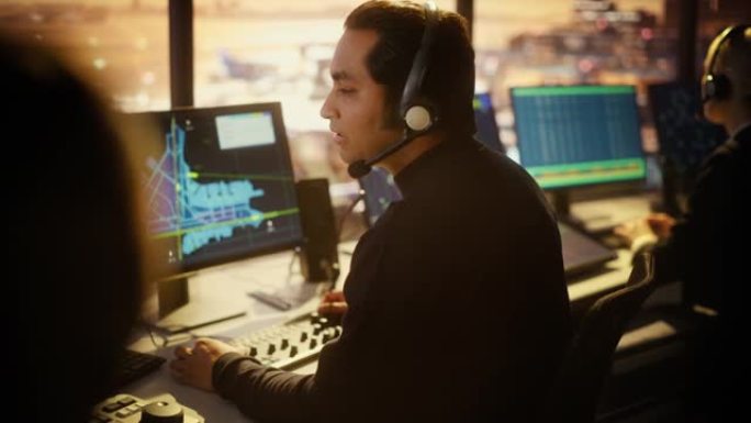 戴着耳机的男性空中交通管制员的肖像在机场塔台通话。办公室里满是台式电脑显示屏，配有导航屏幕、飞机飞行