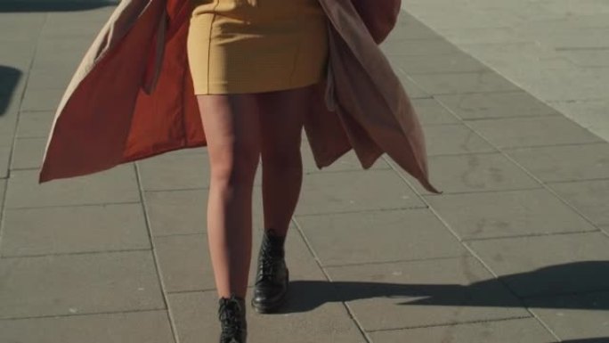 倾斜在美丽的年轻时尚的时尚博客作者女人走在阳光明媚的广场与cofee和电话慢动作。