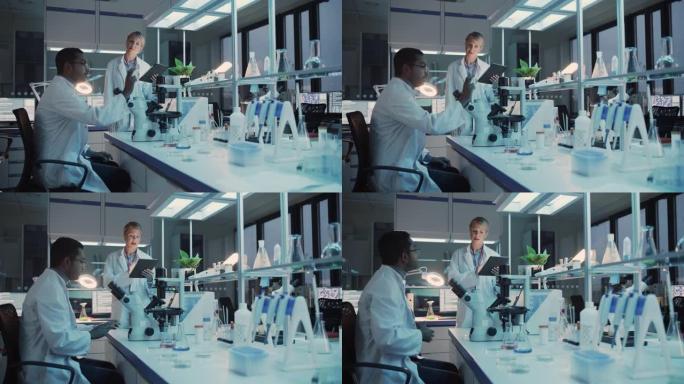 女性和男性医学研究科学家在显微镜下进行实验时进行对话，在平板电脑上写下分析结果。现代生物科学实验室。