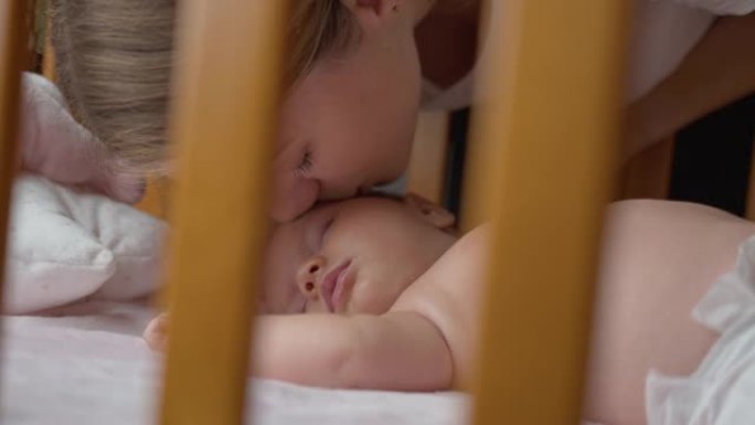 SLO MO深情的年轻母亲在婴儿床上睡觉时亲吻她的婴儿男孩