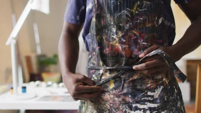 非裔美国男画家在艺术家工作室系围裙
