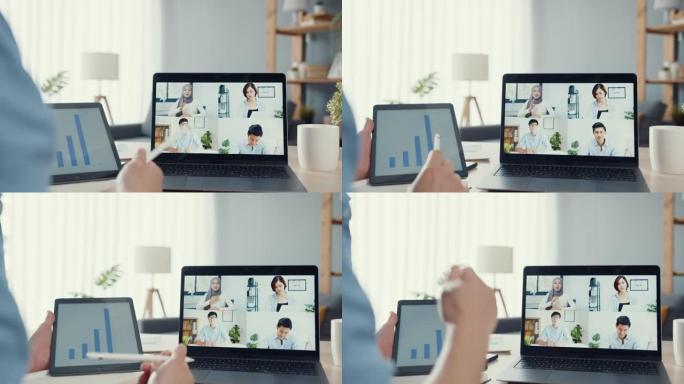 年轻的亚洲商人在客厅在家工作时，使用笔记本电脑与同事讨论视频通话会议的计划。