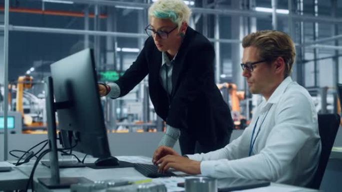 两名汽车工程师在装配厂的现代办公室中讨论台式计算机上的概念车蓝图。女工业项目经理与车辆厂的男设计师交