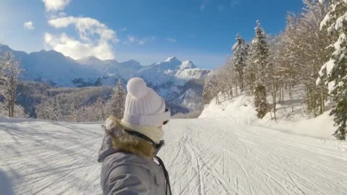 自拍照: 女性滑雪者在阳光明媚的冬日沿着整洁的斜坡巡游。