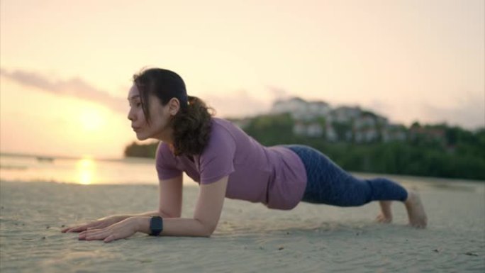 亚洲运动女子在海滩上锻炼木板