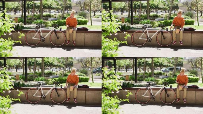 体贴的白化病非裔美国男子，长发lock坐在公园里，用智能手机骑自行车