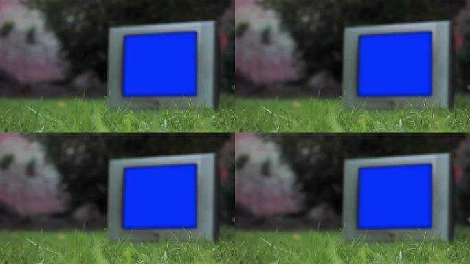 绿色草地上蓝屏的旧模糊电视。