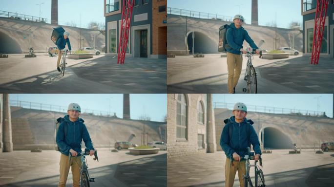 英俊快乐的送餐男子戴着保暖背包，安全帽骑着自行车穿过时尚的现代市区。微笑快递员递送餐厅订单的肖像。慢