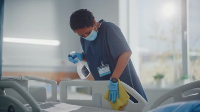 医院病房: 专业的黑人护士戴着口罩，擦拭床铺，清洁房间后新型冠状病毒肺炎患者康复。冠状病毒感染者后的