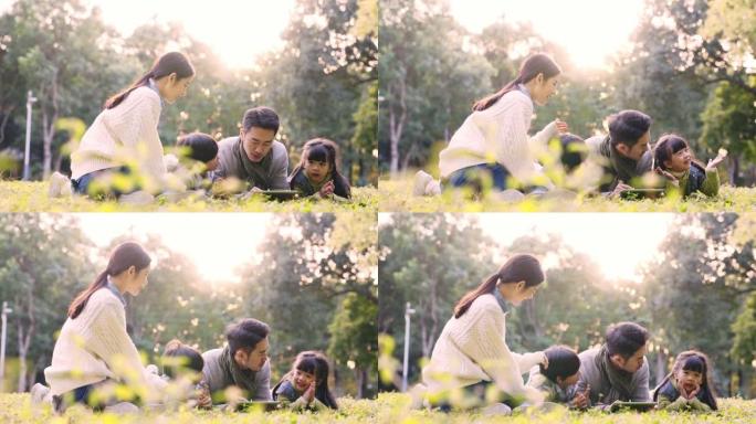 年轻的亚洲家庭在公园的草地上放松户外