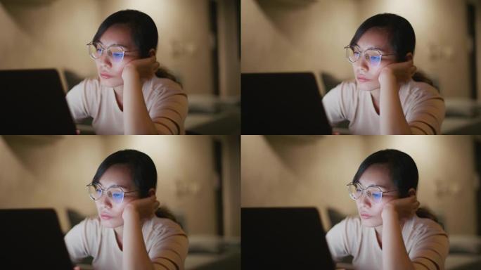 在深夜工作中使用笔记本电脑时，亚洲妇女看上去很无聊