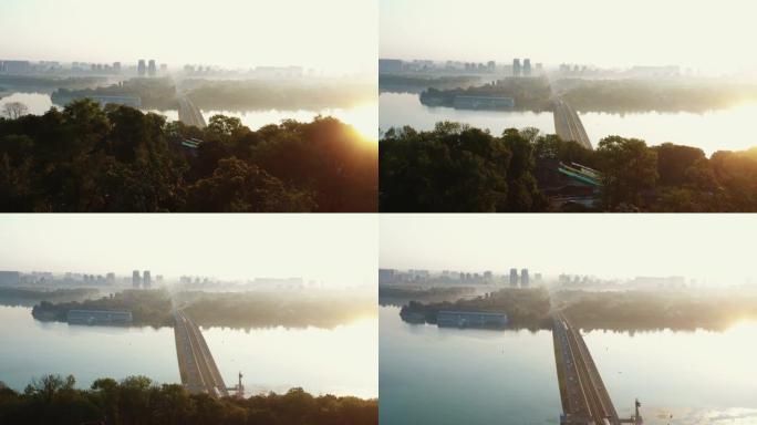 无人机飞过夏季的树木，展示了令人惊叹的汽车桥，第聂伯河上的火车，田园般的夏季日出基辅。