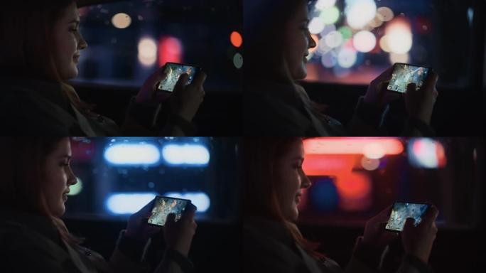 快乐的女性晚上坐出租车后座回家。美丽的女人乘客在智能手机上玩策略视频游戏，而在城市街道上的一辆带有工