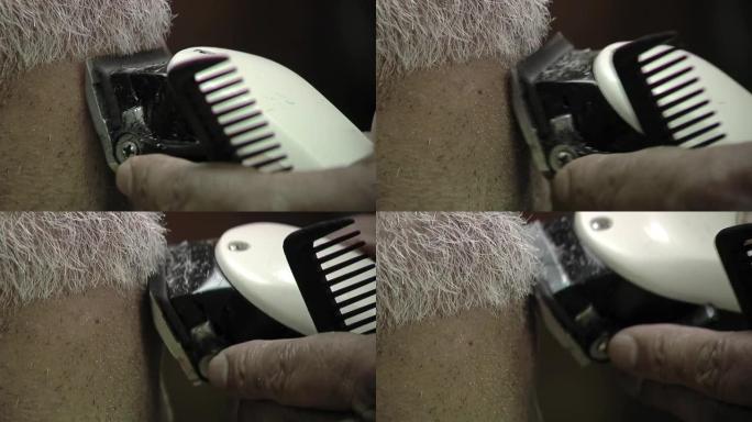 理发师用机器给坐在理发椅上的顾客理发。特写。