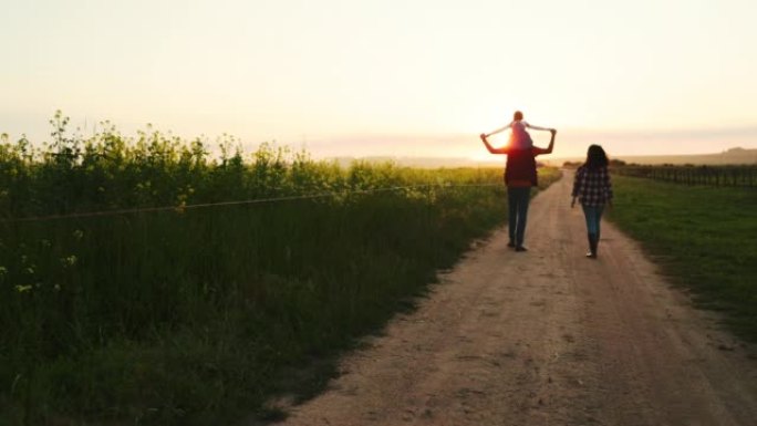 日落时分，一家人沿着农场散步，在大自然中尽情享受。农业，幸福的家庭以及与父母和孩子交谈，放松和欣赏风