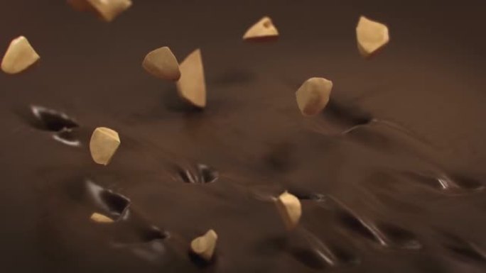 榛子碎片在4k超慢动作中溅到液态牛奶巧克力中