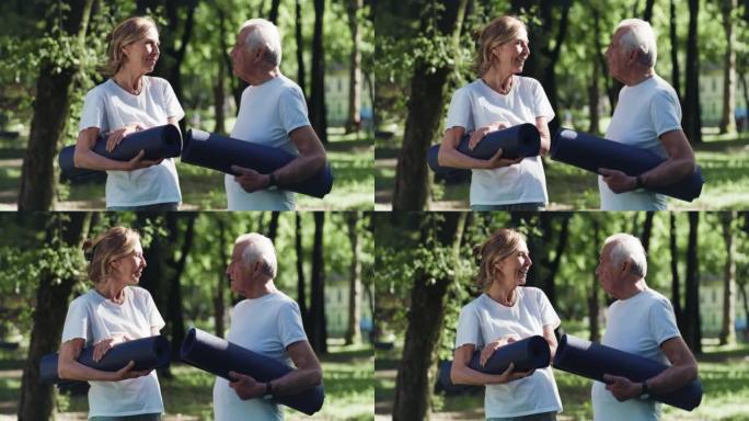 在绿色公园开始锻炼之前，微笑的高级夫妇拿着体操垫的电影镜头。健康生活方式，健身，娱乐，夫妻目标，幸福