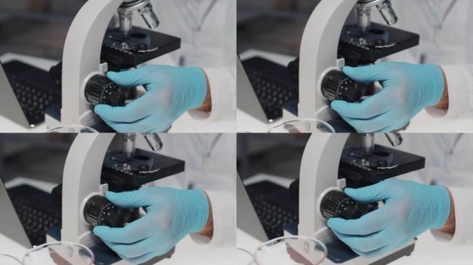 调查期间，研究人员在显微镜上调节表盘的戴手套手