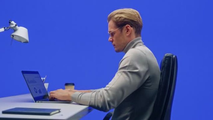 办公室绿屏背景: 商人坐在办公桌前在笔记本电脑上工作。从事大数据电子商务分析的人。360度色度键跟踪