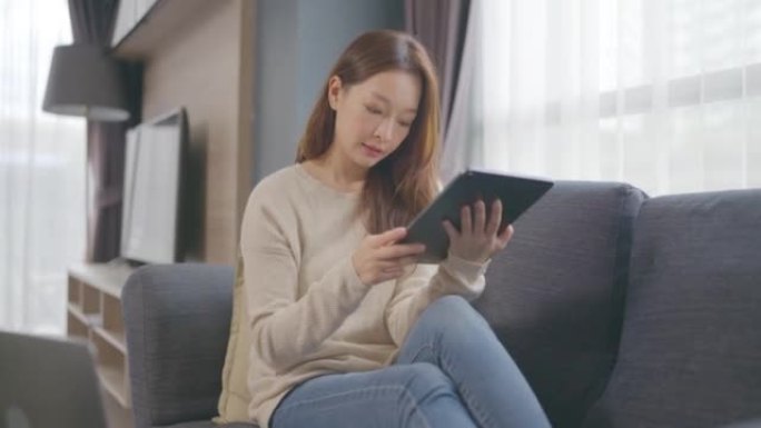 美丽的亚洲年轻女性年龄36岁在家工作数字平板电脑在家。成人在线学习概念。与阿尔法香奈儿。
