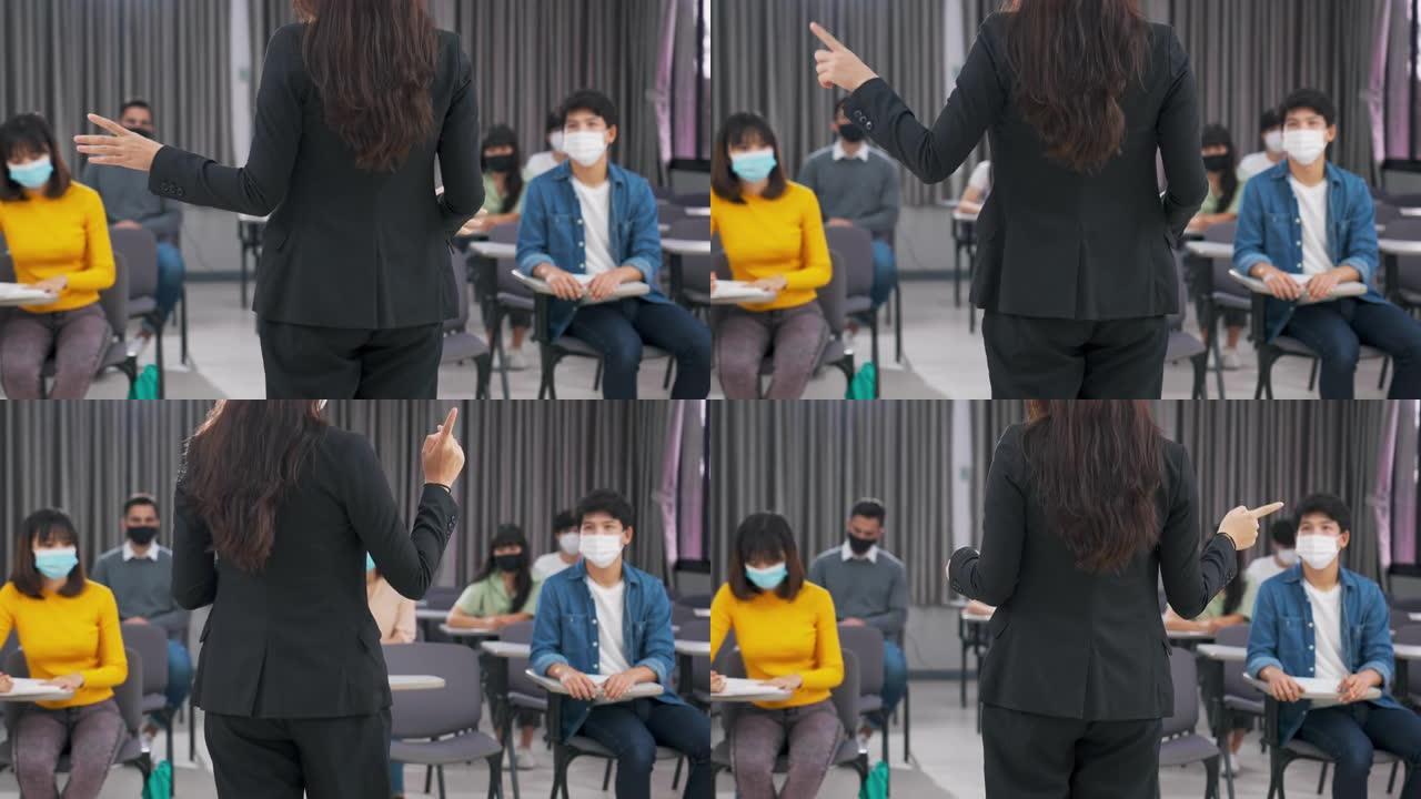 在社交距离的教室中，教师向学生讲解和教学的后视图，在新型冠状病毒肺炎期间返回学校