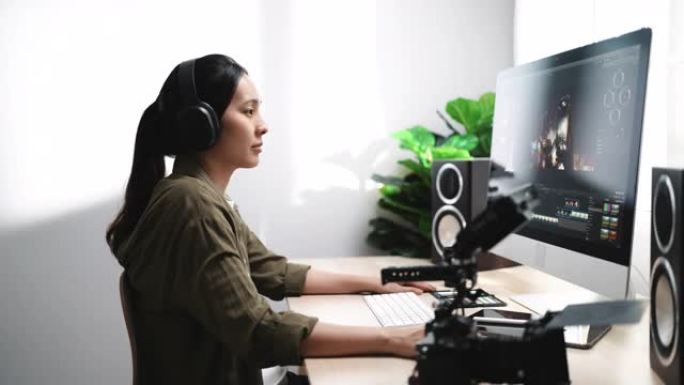 后期制作-女性视频编辑器在带耳机的计算机上进行视频编辑
