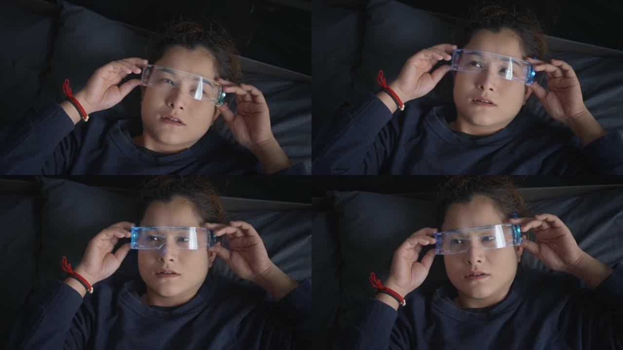 亚洲女性使用虚拟现实眼镜躺在床上，赛博朋克眼镜