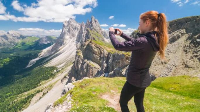 山顶上的女徒步旅行者用智能手机拍摄令人叹为观止的景色