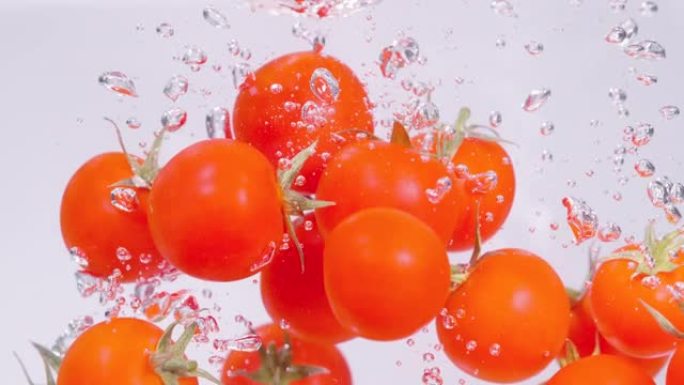 特写: 充满活力的红色樱桃番茄落入清澈的淡水中。
